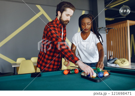 Black girl in a white t-shirt. Couple playing a billiard 121698471