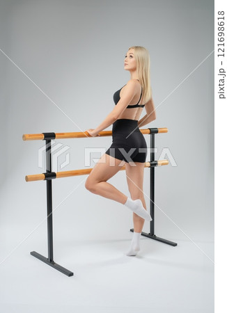 Young woman practicing ballet at a dance studio with a ballet barre Young woman practicing ballet at a dance studio with a ballet barre 121698618