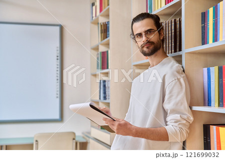 Portrait young male with clipboard in library 121699032