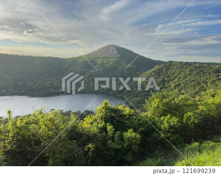 Majestic volcanic landscape with serene lake and lush greenery at sunset 121699239