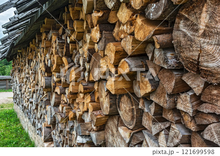 Chopped firewood is packed in a pile of wood under a canopy 121699598