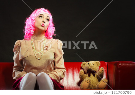 childlike woman and teddy bear sitting on couch childlike woman and teddy bear sitting on couch 121700790