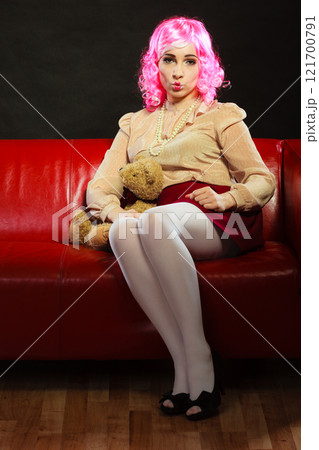 childlike woman and teddy bear sitting on couch 121700791