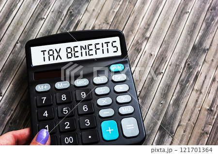 The word "Tax benefits" on the calculator is held by a woman's hand. The concept of business 121701364
