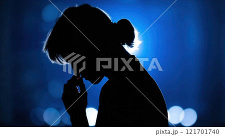 Silhouette of a woman in contemplative pose with blue glowing background, symbolizing introspection and emotional depth 121701740