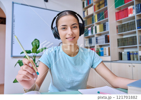 Webcam view of teenage girl, high school student, in headphones, talking to camera 121701882