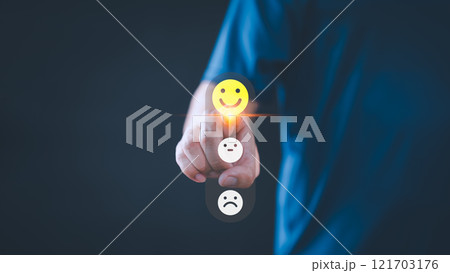 Person selects a happy face icon from a feedback scale with three emoji options, symbolizing customer satisfaction, review, and positive user experience, decision-making in an online feedback system. 121703176