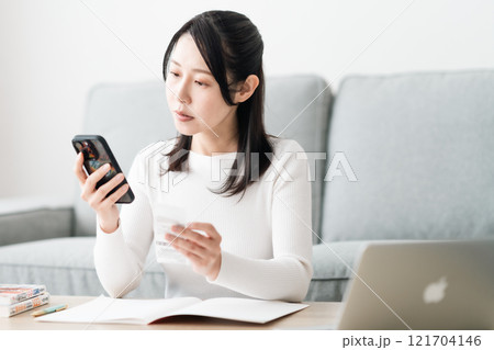 スマホで家計簿をつけるミドルの女性 スマホで家計簿をつけるミドルの女性 121704146