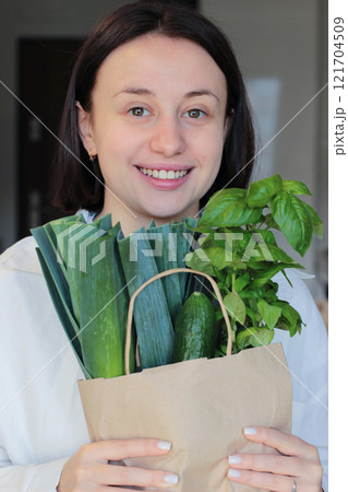 A girl with a package of green vegetables. A happy girl carries home a paper bag of greens A girl with a package of green vegetables. A happy girl carries home a paper bag of greens 121704509