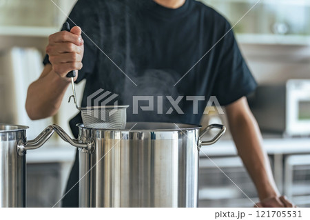 厨房で麺を茹でる飲食店店員 121705531