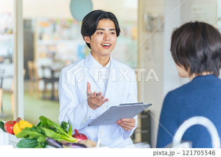 女性に野菜や果物を勧める若い白衣の男性 管理栄養士 女性に野菜や果物を勧める若い白衣の男性 管理栄養士 121705546