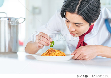 厨房で料理を盛り付ける男性シェフ 121705559