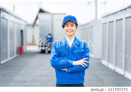 コンテナ倉庫の前に立つ男性作業員 121705575