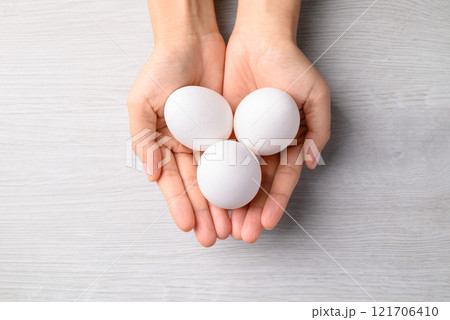 White eggs in by hand on white background, Table top view White eggs in by hand on white background, Table top view 121706410