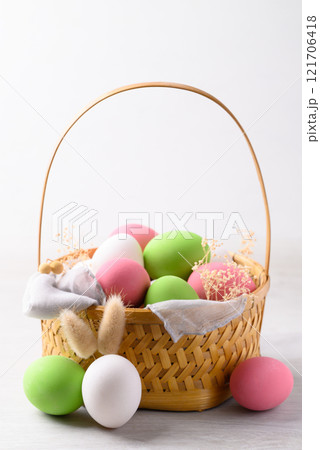 White easter eggs with bunny rabbit ears and colorful easter eggs in basket on white background White easter eggs with bunny rabbit ears and colorful easter eggs in basket on white background 121706418