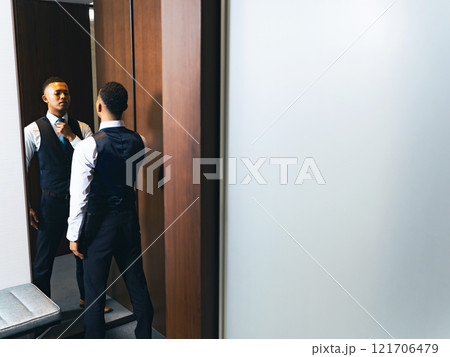 鏡を見て身だしなみを整える外国人男性 121706479