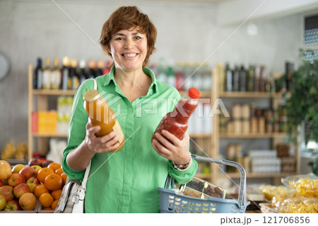 Woman hold packages bottles and choose consider juice in store 121706856