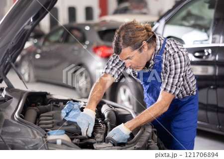 Mechanic man in uniform repairing car in auto repair shop garage Mechanic man in uniform repairing car in auto repair shop garage 121706894