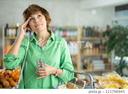 Adult woman with headache pills in grocery store 121706945