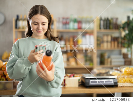 Teenage girl scanning qr code of grapefruit juice Teenage girl scanning qr code of grapefruit juice 121706988