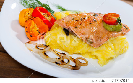 Fried trout fillet served mashed potatoes, peppers and greens on plate 121707034