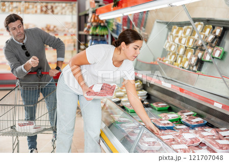 Married couple choosing meat together in the meat department of supermarket 121707048