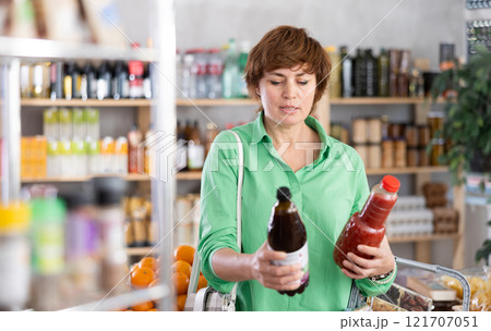 Grocery shopping at supermarket - woman chooses juice, tomato, grapefruit or peach 121707051