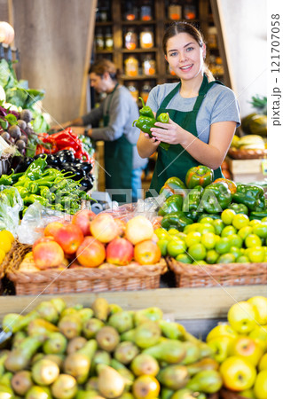 Young woman selling green capsicum in shop Young woman selling green capsicum in shop 121707058