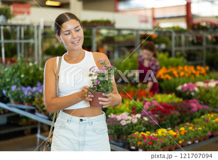 Young girl holding flower-pot with pentas in large plants market 121707094