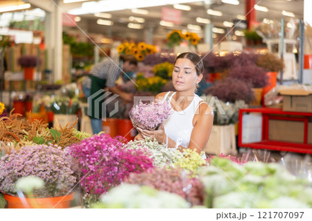 Girl customer in flower shop chooses dry flowers to form ikebana 121707097