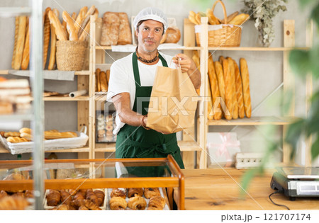 Middle-aged salesman holding paper bag in bakery 121707174