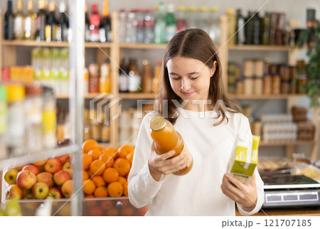 Teenage girl choosing peach and apple juices 121707185