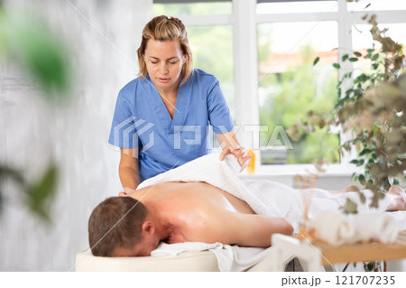 the woman ensures the man is comfortably covered with a towel for the massage the woman ensures the man is comfortably covered with a towel for the massage 121707235