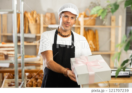 Middle-aged salesman holding cake box in bakery 121707239