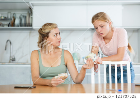Mother gives teenage daughter bills small amount of pocket money. 121707328