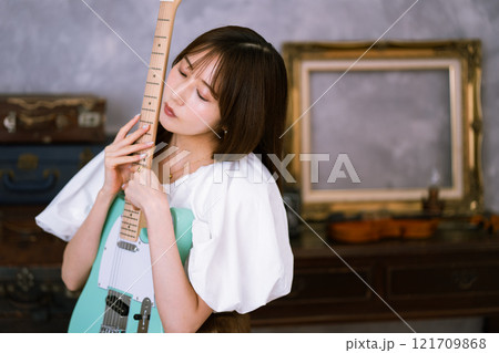 エレキギターを持つロングヘアの若い女性 121709868