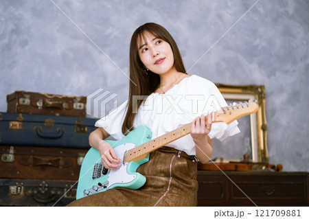エレキギターを持つロングヘアの若い女性 121709881