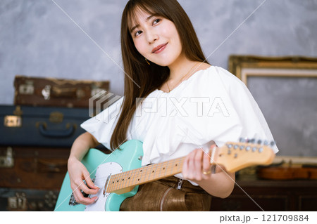 エレキギターを持つロングヘアの若い女性 121709884
