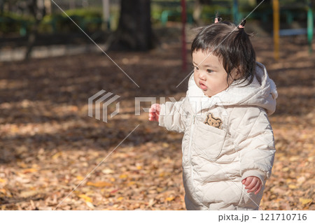 【落ち葉で敷き詰められた冬の公園で遊ぶ1歳児　立つ】 121710716
