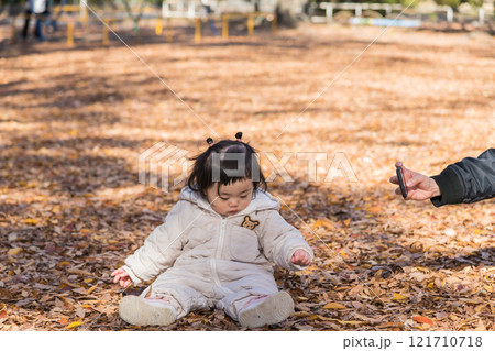 【落ち葉で敷き詰められた冬の公園で遊ぶ1歳児 立つスマホ】 【落ち葉で敷き詰められた冬の公園で遊ぶ1歳児 立つスマホ】 121710718