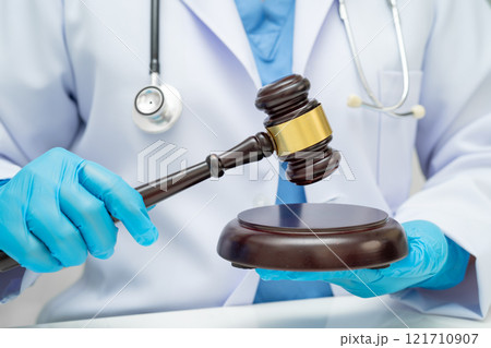 Asian doctor holding court hammer for and crime law justice, forensic medicine. Asian doctor holding court hammer for and crime law justice, forensic medicine. 121710907
