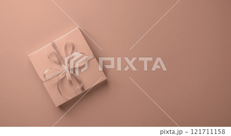 Elegant gift box with silver ribbon on soft pastel brown background Elegant gift box with silver ribbon on soft pastel brown background 121711158