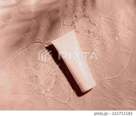 Minimalist beige skincare tube floating on rippling water surface 121711165