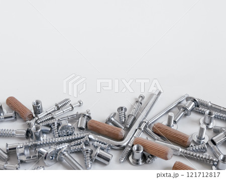 Assorted metal screws and wooden dowels on a white surface Assorted metal screws and wooden dowels on a white surface 121712817