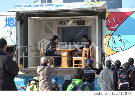 地震体験車「ゆれるん」　揺れを体験する家族　　 121713077