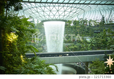 Rain vortex waterfall cascading inside jewel changi airport surrounded by lush greenery Rain vortex waterfall cascading inside jewel changi airport surrounded by lush greenery 121713360