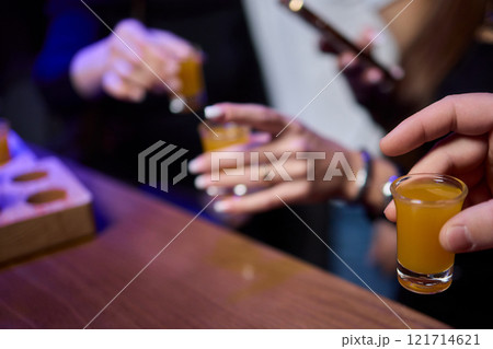 A woman holds a cocktail in her hand, with her fingers wrapped around the glass A woman holds a cocktail in her hand, with her fingers wrapped around the glass 121714621