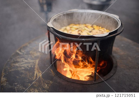 The Glow of Embers and Flames in a Steel Cooking Pot Outdoors Under the Starry Sky The Glow of Embers and Flames in a Steel Cooking Pot Outdoors Under the Starry Sky 121715051