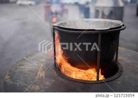 The Glow of Embers and Flames in a Steel Cooking Pot Outdoors Under the Starry Sky 121715054