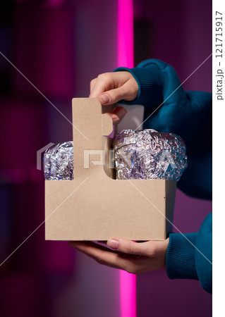 Hands holding a stylish brown paper basket that features a shiny metallic foil lid design 121715917